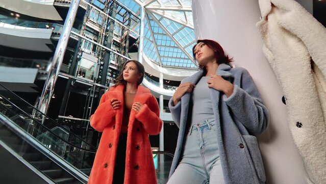 Two female fashion model trendy fur coat presenting couture collection at multilevel shopping center