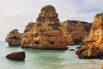 Large rocks in the water at a sandy beach in southern Portugal on a winter day.