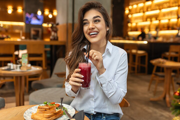 Cute young woman taking a smoothie break at a juice bar, Cheerful young woman having lunch and...