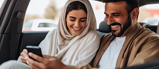 Happy Middle Eastern couple in car, setting GPS on phone, looking at screen together.
