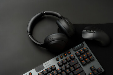 Headphones, computer mouse and keyboard on black background - obrazy, fototapety, plakaty