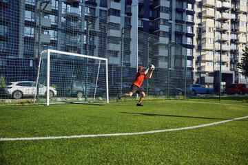 Young man catching soccer ball in gate while training on field