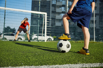 Father goal keeper and schoolboy son forward training football at stadium