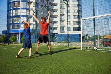 Excited dad and son rejoicing win in football match celebrating victory