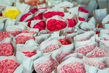 Many bouquets of flowers of various colored red pink and white shades of chrysanthemum and carnation flowers. Bouquets in paper bags for wholesale and retail sale.