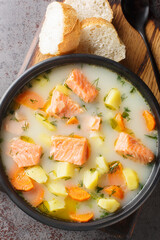 Finnish wild salmon soup with cream and root vegetables close-up on a plate on the table. Vertical top view from above