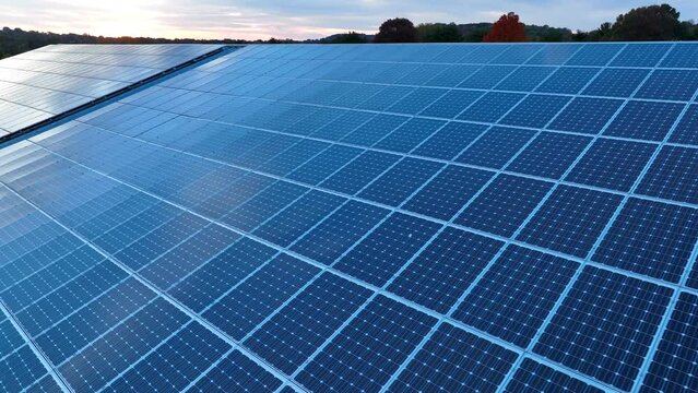 Large rooftop solar panel array during sunset. Aerial close up. Green energy theme.