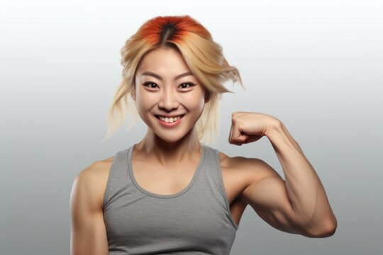 A woman with a smile on her face showcasing her muscular strength. Can be used to depict confidence, fitness, and empowerment