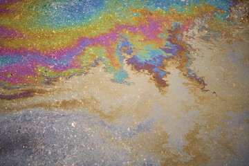 Abstract colored background of leaked gasoline on wet asphalt close-up