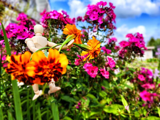 Wooden toy man with flowers against background grass in nature. Concept of holiday, gift bouquet, Valentine's Day, proposal, engagement, declaration of love, Mother's Day. Caring, loving, romantic