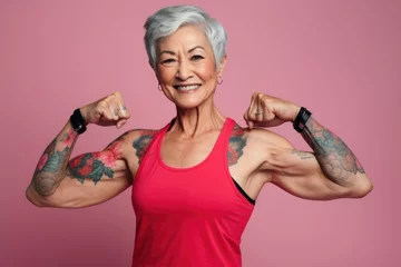 Foto op Plexiglas An older woman showcasing her strength by flexing her muscles. This image can be used to promote fitness and healthy aging © Fotograf