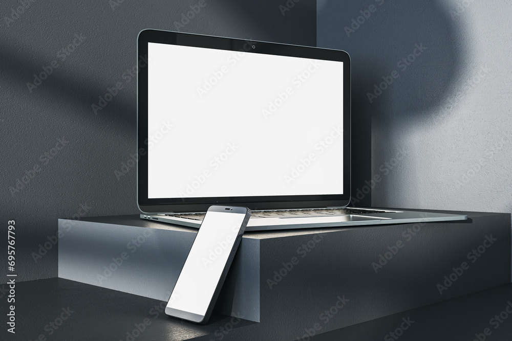 Poster close up of empty white laptop and smartphone on dark gray desk. concrete wall background, shadows a