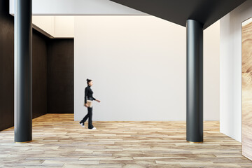 Side view of businessman walking in modern hallway interior with columns, blank white mock up lace...