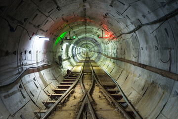 Soft focus of Underground tunnel construction. Transport pipeline by Tunnel Boring Machine for electric train subway with lighting.