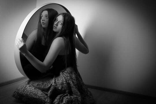 young woman looks in the mirror - art photo