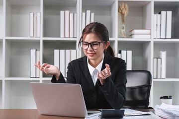 Young Asian woman using laptop to do financial transaction and plan finances and investments through online banking