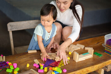 toddler girl playing toy with her mother on table