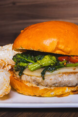 Panino da pub con hamburger di maialino nero, provolone del monaco, friarielli, pomodorini confit e lardo di colonnata servito in una braceria con contorno di pop corn di cotica di maiale