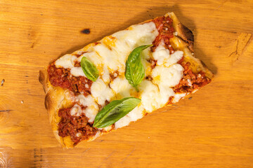 Fetta di Pinsa Romana condita con sugo di pomodoro, mozzarella e basilico fresco