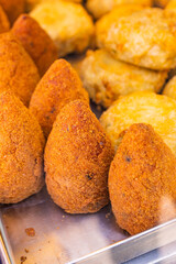 Arancino di riso fritto e frittatine di pasta fritte tradizionali napoletane in una vetrina da vendita di una pizzeria e pronti per essere venduti