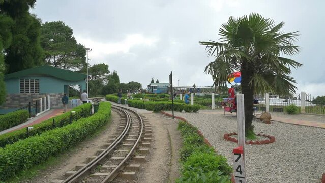 Darjeeling,West Bengal,India- 20.08.2023 : Famous Diesel Toy train passing through Batasia loop, memorial to Indian Army. Unesco world heritage toy train of Darjeeling Himalayan Railway, narrow gauge.