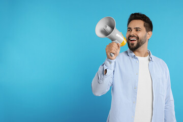 Special promotion. Smiling man with megaphone on light blue background. Space for text