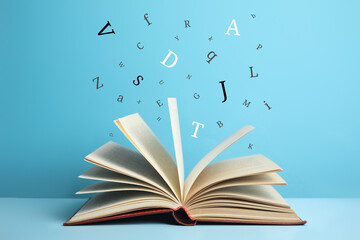 Open book with letters flying out of it on light blue background