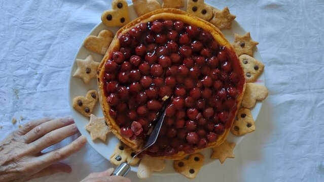 Cheesecake with cherries surrounded by small heart and star shaped cookies