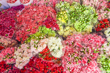 Many bouquets of flowers of various colored red pink and white shades of chrysanthemum and carnation flowers.