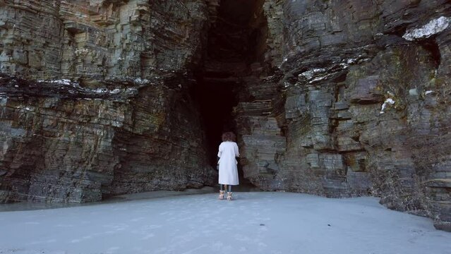 Tourist woman photographing one of the most beautiful natural enclaves of Lugo, known as Playa de las Catedrales, offers an impressive view of cuavar formed by the erosion of water on the rock.