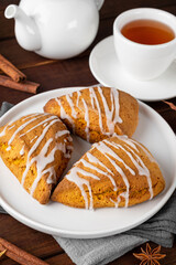 Traditional pumpkin scones with cinnamon, anise and sugar glaze on top. Autumn dessert.
