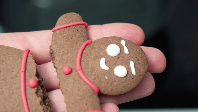 Hands holding a homemade broken gingerbread man. Close up
