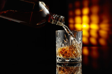 Pouring whiskey from a bottle into a glass.