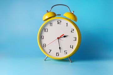 Retro style alarm clock over blue color background .