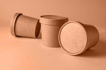 Empty paper Biodegradable cups containers for food and soup on the background of Trendy color of year 2024 - Peach Fuzz.
