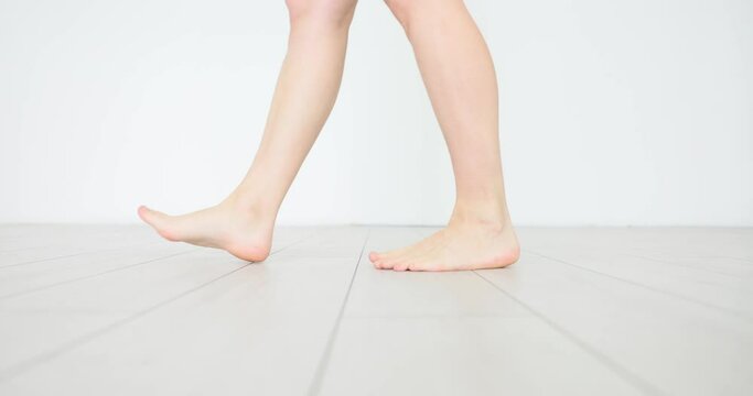 Woman walks naked on laminate flooring indoors. High quality underfloor heating