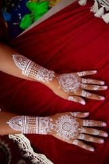 White bridal henna tattoos on two hands on red background. Moroccan wedding preparation henna...