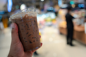 Close up view of iced Mocha coffee against blur image of department store background.