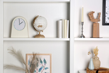 White shelves with books, globe and different decor indoors. Interior design - obrazy, fototapety, plakaty