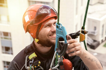 Industrial mountaineering worker hangs over residential facade