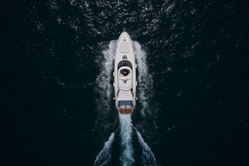 Mega large White yacht moves through dark water, top view. Large high-speed White yacht moving on...