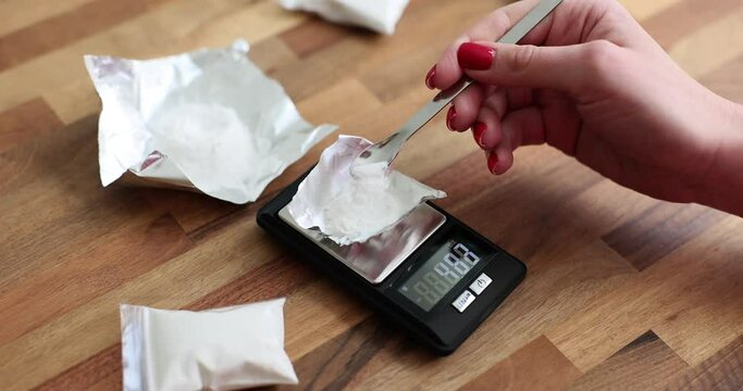 Persons weigh white powder on an electronic scale. Drug dealer pack up a dose of drugs