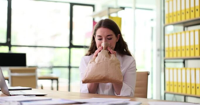 Frightened woman breathing into paper bag at workplace. Panic attack at work
