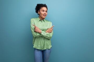 young brunette hispanic woman with curly hair in a green blouse on a blue background with copy space