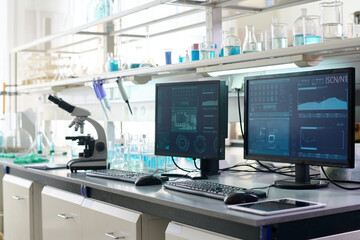 Medium shot of laboratory technicians desk with operating computers running through medical research