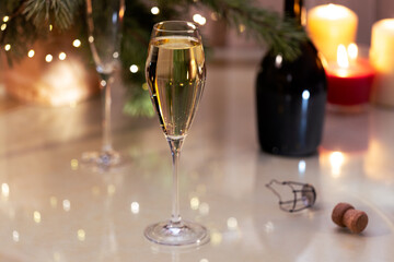 Glass of sparkling champagne wine on christmas background with pine branch and blinking lights