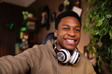 Portrait of delighted smiley with beautiful white teeth african american dark skinned man guy podcast host, preparing to record his next episode in the cozy living room holding cellphone in hands.