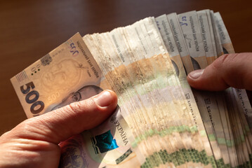 Male hands holding a big stack of ukrainian 500 banknotes, counting them. Good earnings, wealth, savings and payments concepts