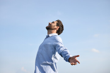 Happy man enjoying feeling of freedom against sky outdoors