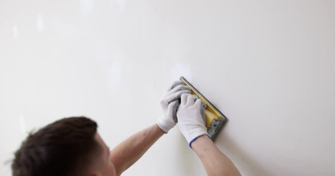 Repair of apartment and processing of wall with sandpaper. Plastering and leveling walls